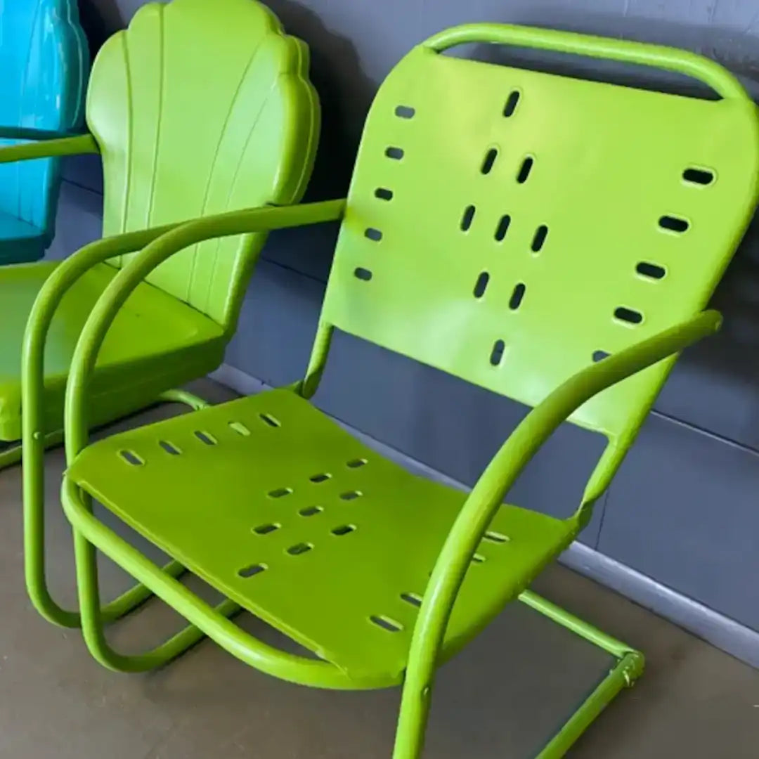 Bright green metal outdoor chair with armrests and slotted back and seat.