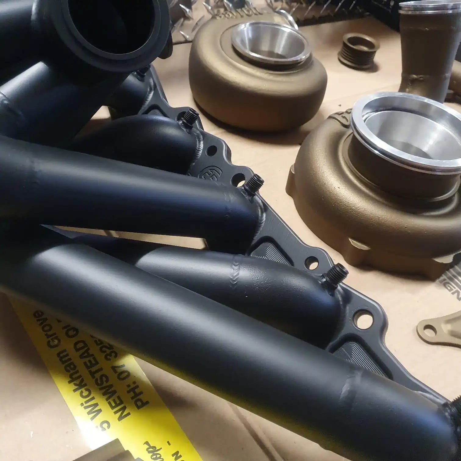 Matte black exhaust headers with two bronze turbochargers.